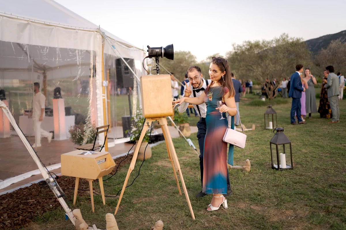 Couple posant devant la borne photobooth en bois et son flash professionnel lors d'un mariage en extérieur à Marseille